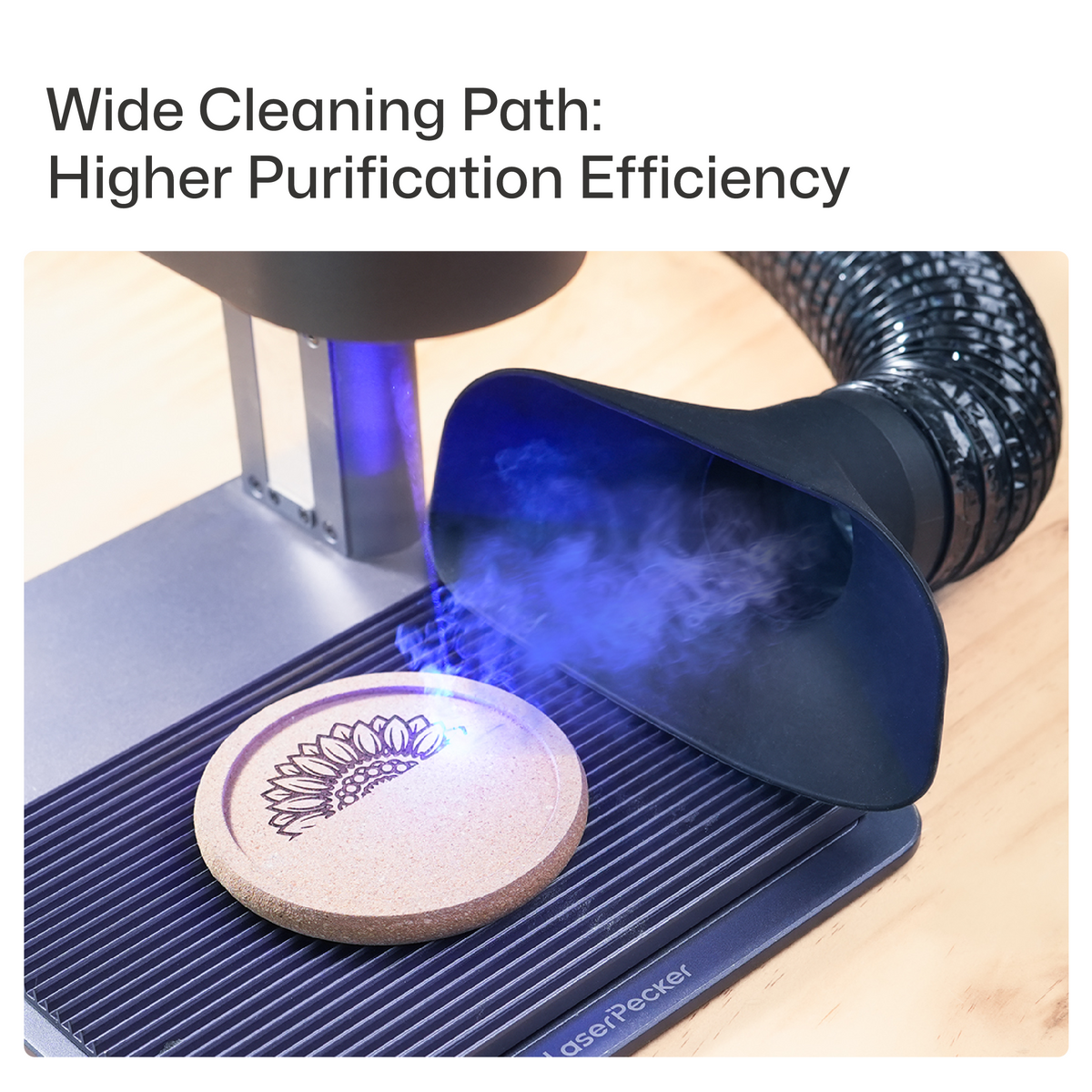 Dust Hood Collector in use with a LaserPecker laser engraver, efficiently capturing smoke and debris from the engraving of a sunflower design on a cork coaster, demonstrating its wide cleaning path and high purification efficiency.