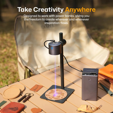 LaserPecker laser engraver powered by portable power bank on wooden surface outdoors — take creativity anywhere with freedom to create whenever inspiration flows. 