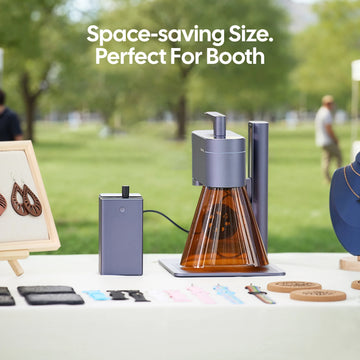 LaserPecker LP4 featuring both a diode laser cutter and an IR laser engraver, set up at an outdoor craft booth. Highlighting its compact, space-saving design ideal for markets and pop-up events, paired with a portable power supply and sample engraved crafts.