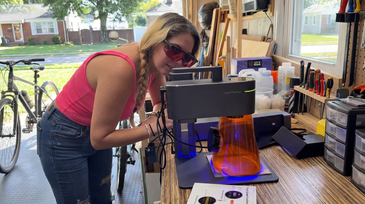 A woman interacting with a laser engraving machine.