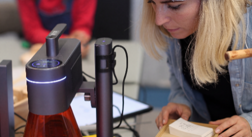 A woman trying a LaserPecker machine to engrave a product.
