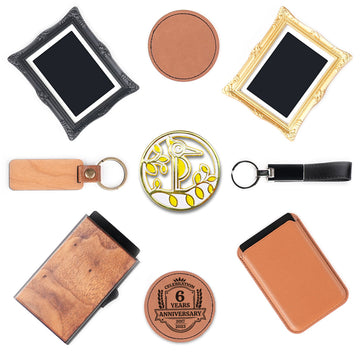 A flat lay of curated gift items and accessories arranged symmetrically on a white background, including an ornate black picture frame, a plain round leather coaster, an ornate gold picture frame, a wooden keychain, a gold enamel pin with a stylized bird and foliage design, a black leather keychain, a wooden cardholder, a leather anniversary coaster engraved with "Celebration 6 Years Anniversary 2017-2023", and a tan leather cardholder.
