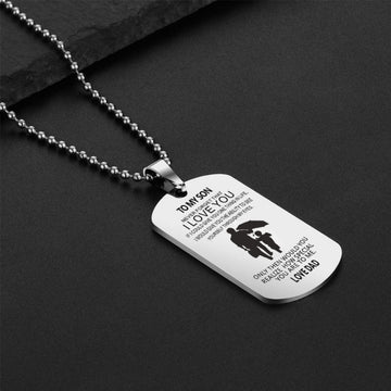 A polished stainless steel dog tag necklace on a beaded ball chain, engraved with a sentimental message from a father to his son: "TO MY SON NEVER FORGET THAT I LOVE YOU IF I COULD GIVE YOU ONE THING IN LIFE, I WOULD GIVE YOU THE ABILITY TO SEE YOURSELF THROUGH MY EYES. ONLY THEN WOULD YOU REALIZE HOW SPECIAL YOU ARE TO ME. LOVE DAD", paired with a silhouette of a father and son.