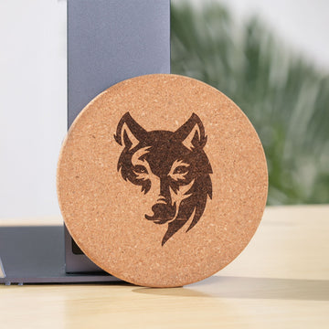 Engraved cork coaster featuring a detailed wolf head design, leaning against a LaserPecker machine stand.
